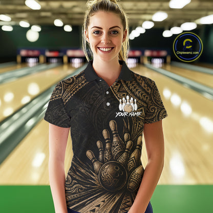 A woman wearing a black short-sleeve polo shirt with a gold bowling-themed graphic print stands in front of a blurred bowling alley background. The shirt features a large bowling hand and ball design, a bowling pins graphic, and the text 'YOUR NAME'.