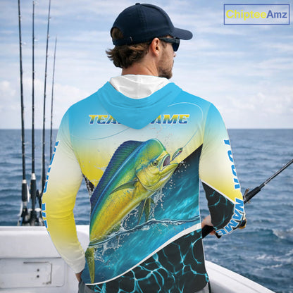 A man on a boat wearing a long-sleeve hooded fishing shirt with a large mahi-mahi fish graphic on the back and 'TEAM name' text across the shoulders. The shirt has a blue-to-yellow gradient with black and white details.