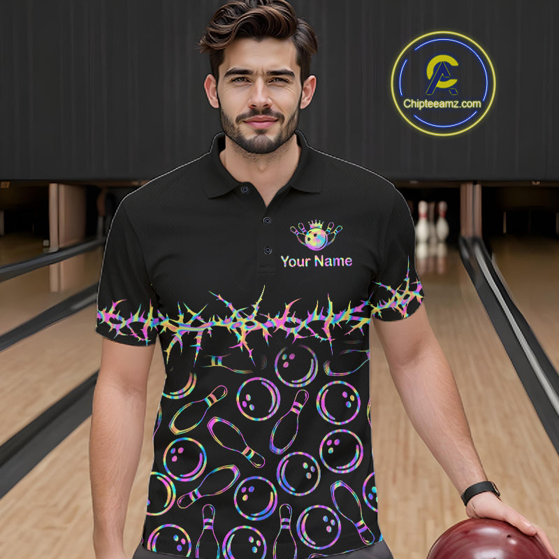 A man wearing a black short-sleeve polo shirt with a colorful bowling-themed print, standing in a bowling alley. The shirt features a rainbow-colored zigzag pattern across the chest and waist, with bowling pins and bowling balls printed below.
