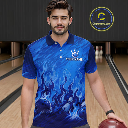 A man wearing a blue short-sleeve polo shirt with a flame and bowling ball graphic, standing in a bowling alley. The shirt has a white crown logo and the text 'YOUR NAME' on the chest.