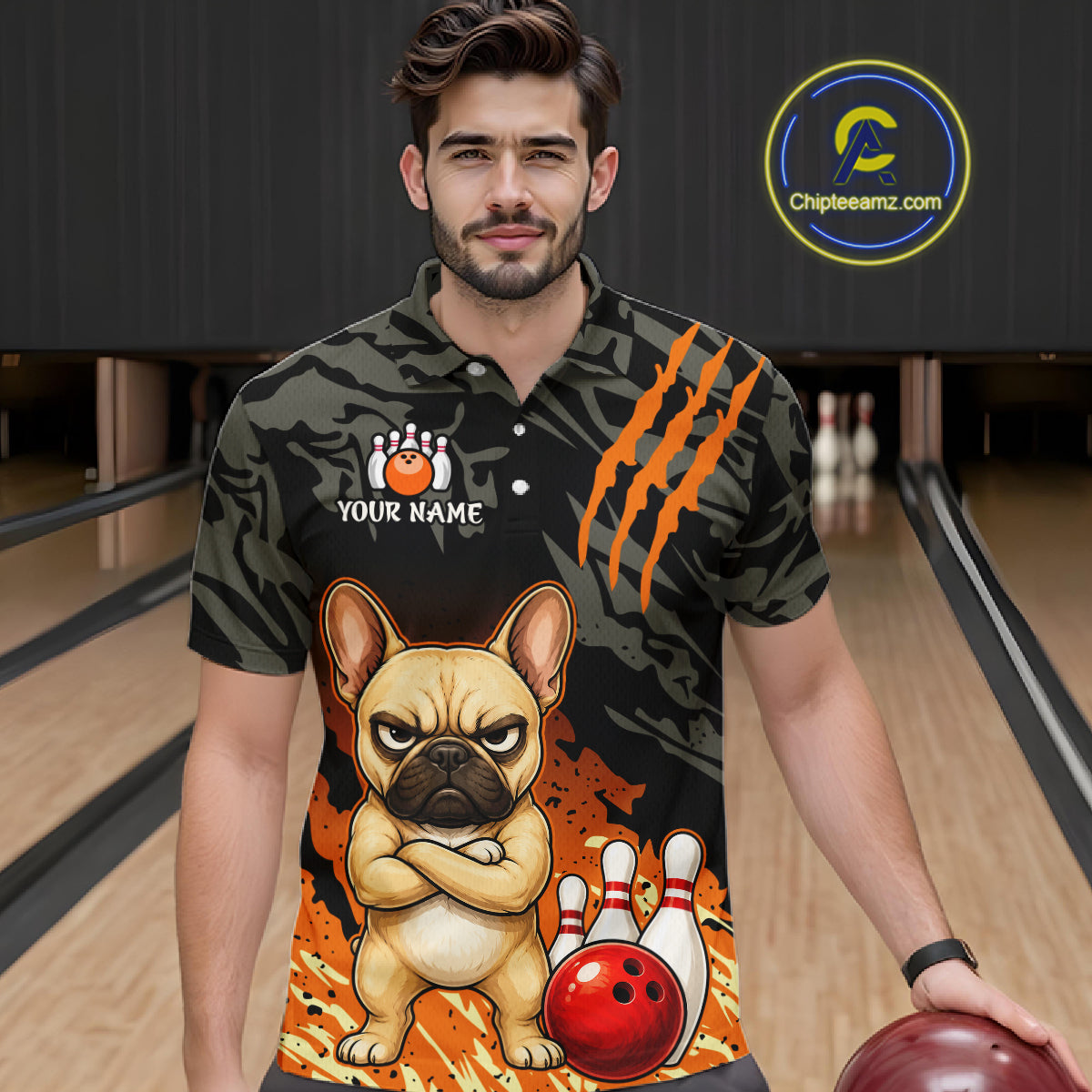 A man in a bowling alley wearing a custom short-sleeve polo shirt with a black camouflage pattern, orange claw marks, a cartoon French bulldog, bowling pins, and a red bowling ball graphic. A circular 'Chipleeamz.