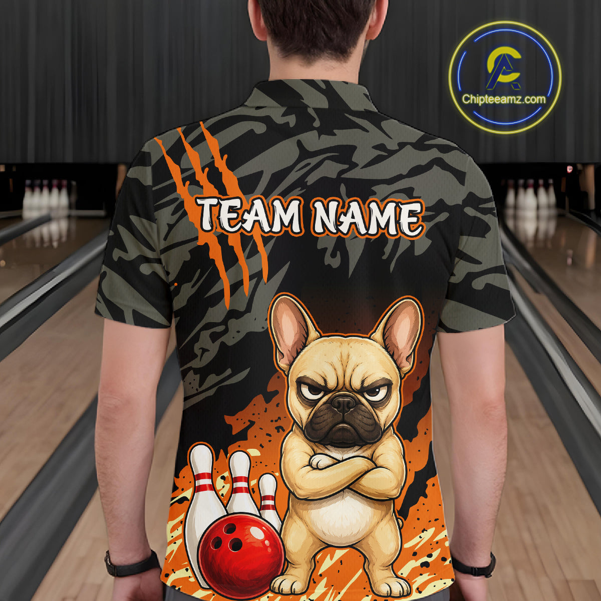 A person viewed from behind wearing a short-sleeve bowling shirt with a custom graphic of a French bulldog and bowling pins. The shirt features a dark camouflage pattern with orange claw marks and the text 'TEAM NAME'.