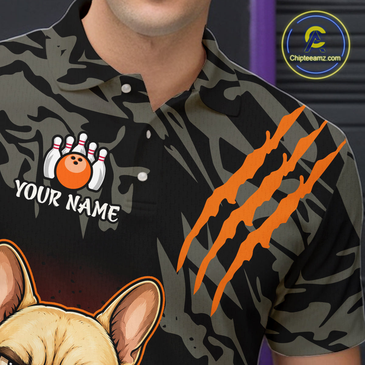 A close-up of a person wearing a short-sleeve polo shirt with a dark camouflage pattern, orange claw marks, a bowling-themed graphic with the text 'YOUR NAME', and part of a dog illustration. A circular 'Chipteaamz.