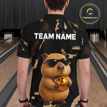 Load image into Gallery viewer, Person wearing a black shirt with a capybara graphic holding a bowling ball in a bowling alley.